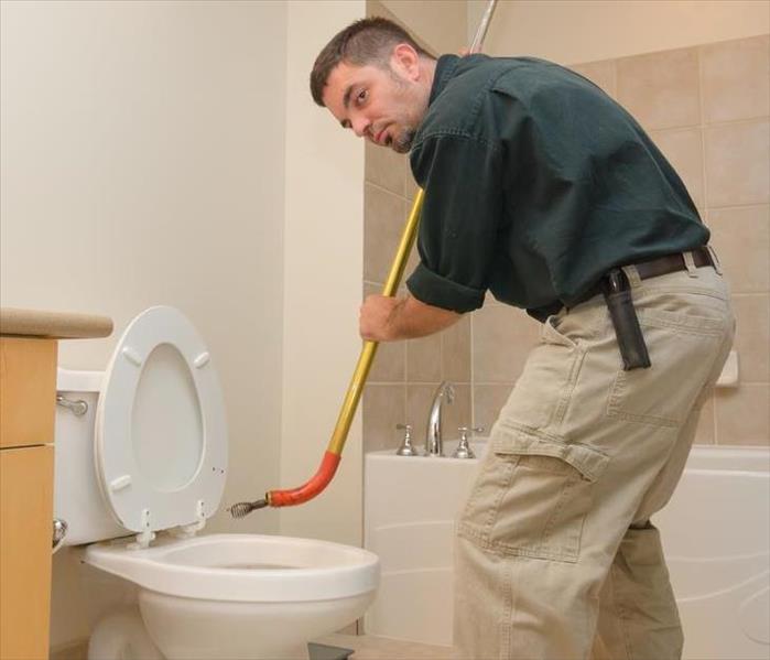  Plumber unclogging a toilet with manual auger
