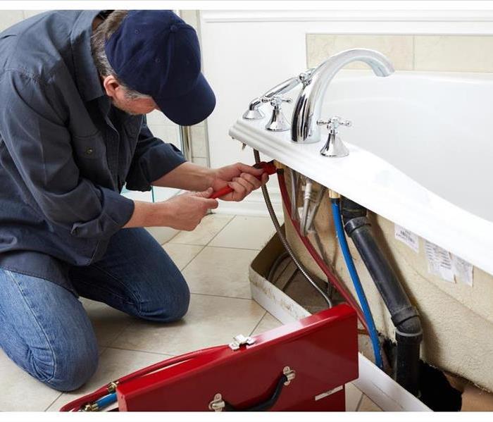 A plumber is checking a bathtub leak