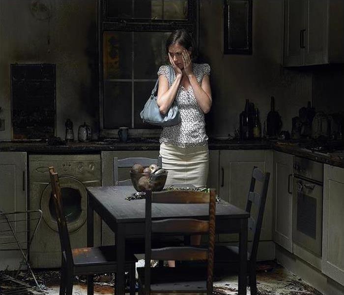 A picture of a burnt kitchen with a woman standing in the center