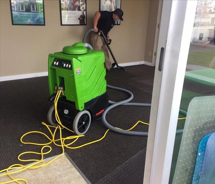 Restoration technician removing water from carpet